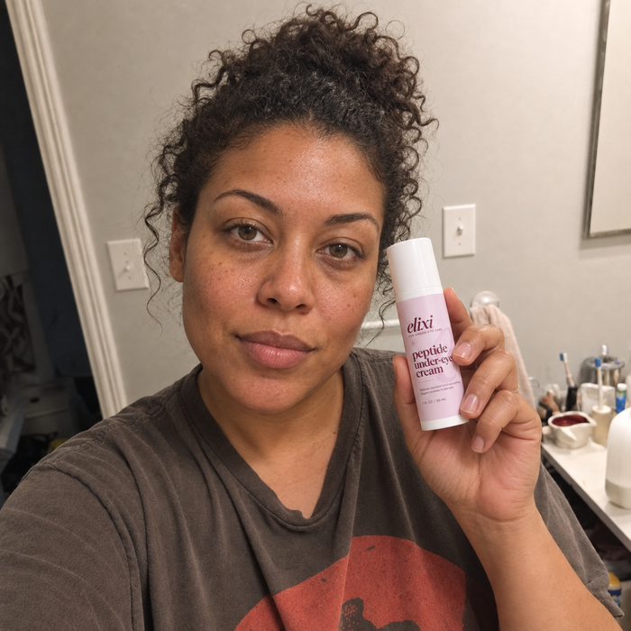 Woman holding Elixi Peptide Under-Eye Cream in a bathroom