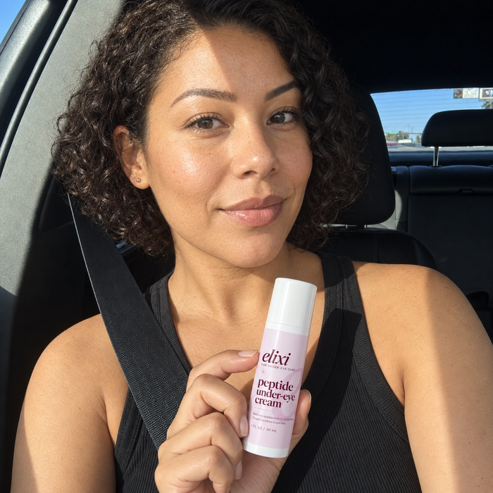 Woman holding Elixi Peptide Under-Eye Cream while seated in a car