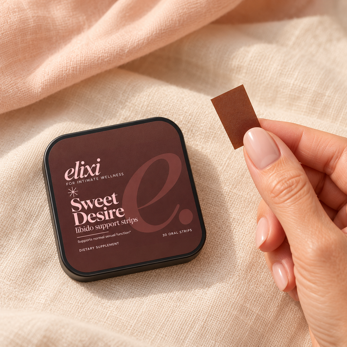 A feminine hand holding a thin oral strip beside the Sweet Desire tin.
